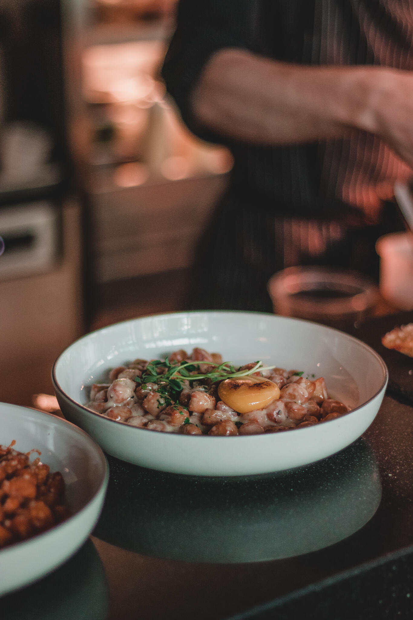 Gather Restaurant A chef in a professional kitchen skillfully preparing ingredients for a Korean Italian meal on a countertop.