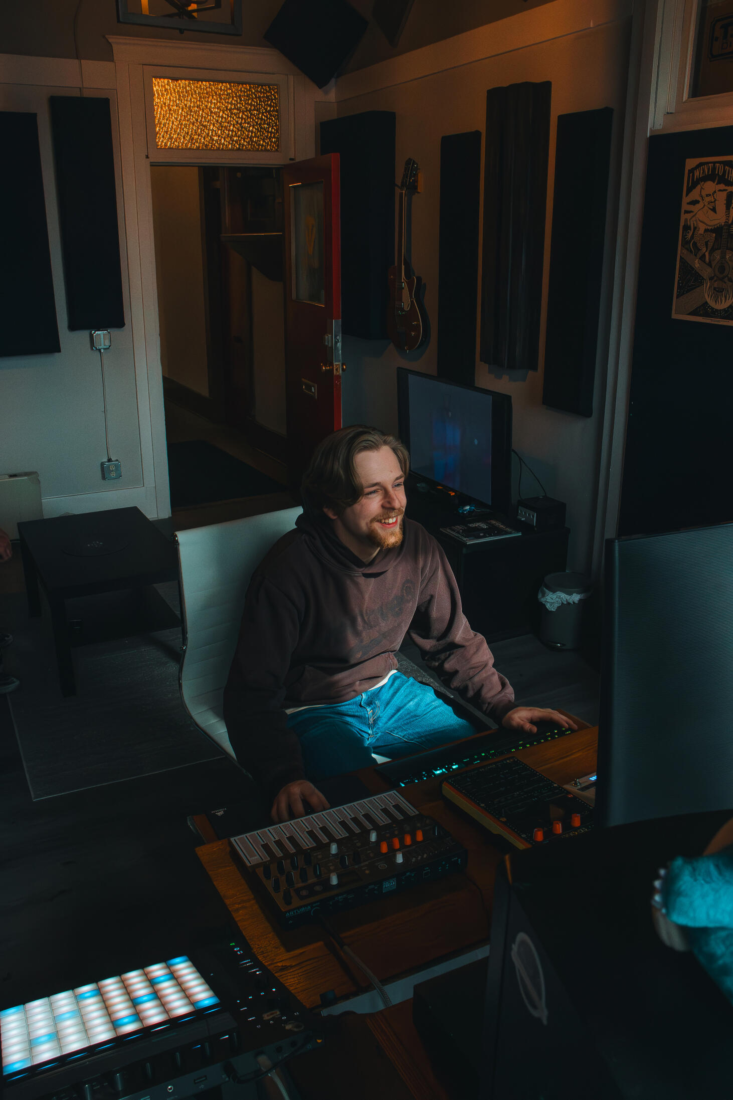 Vault 22 Multiple high-quality MIDI pianos and devices used to produce, mix, and master different music tracks, featured on a clean wood shelf with light shining on them.